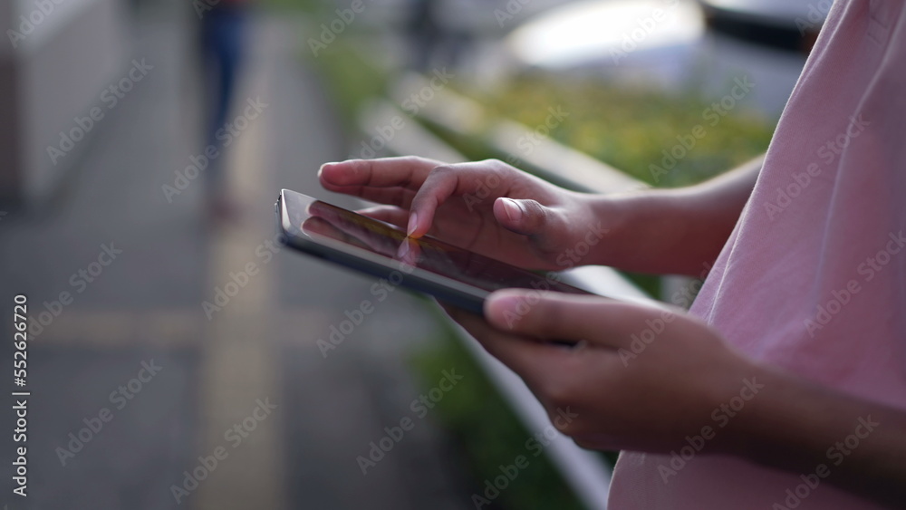 Closeup hand using tablet device outdoors. A hispanic person holding screen Closeup hand using tablet device outdoors. A hispanic person holding screen