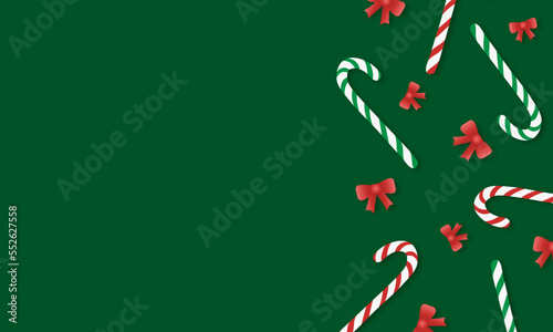 Green background with striped red and green candy canes and red bows with copy space