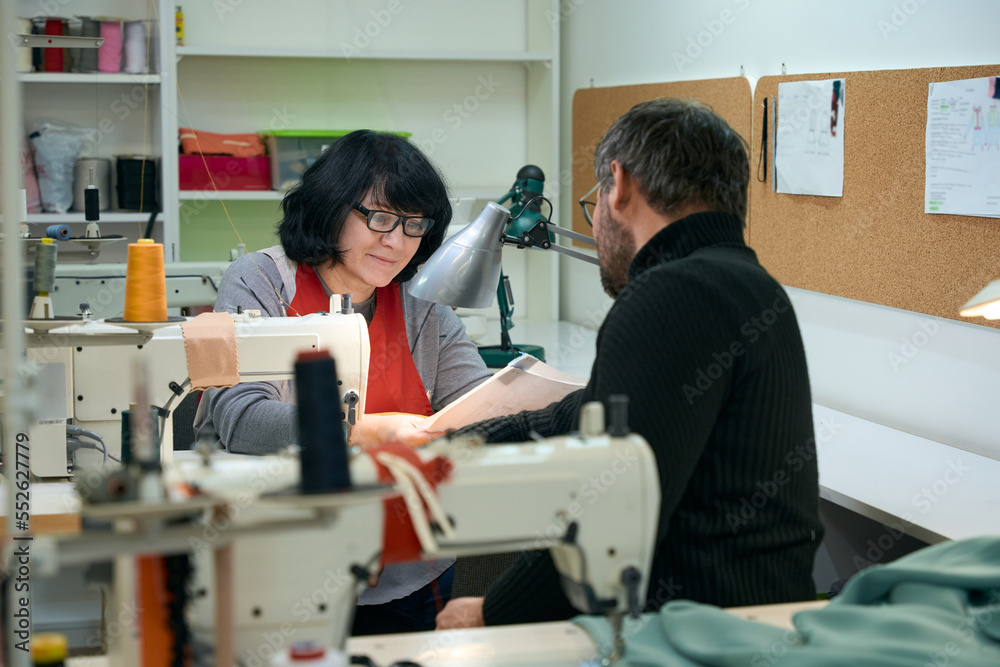 Tailors, a man and a woman, are considering working sketches