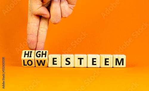 High or low esteem symbol. Concept words High esteem and Low esteem on wooden cubes. Businessman hand. Beautiful orange table orange background. Business high or low esteem concept. Copy space.