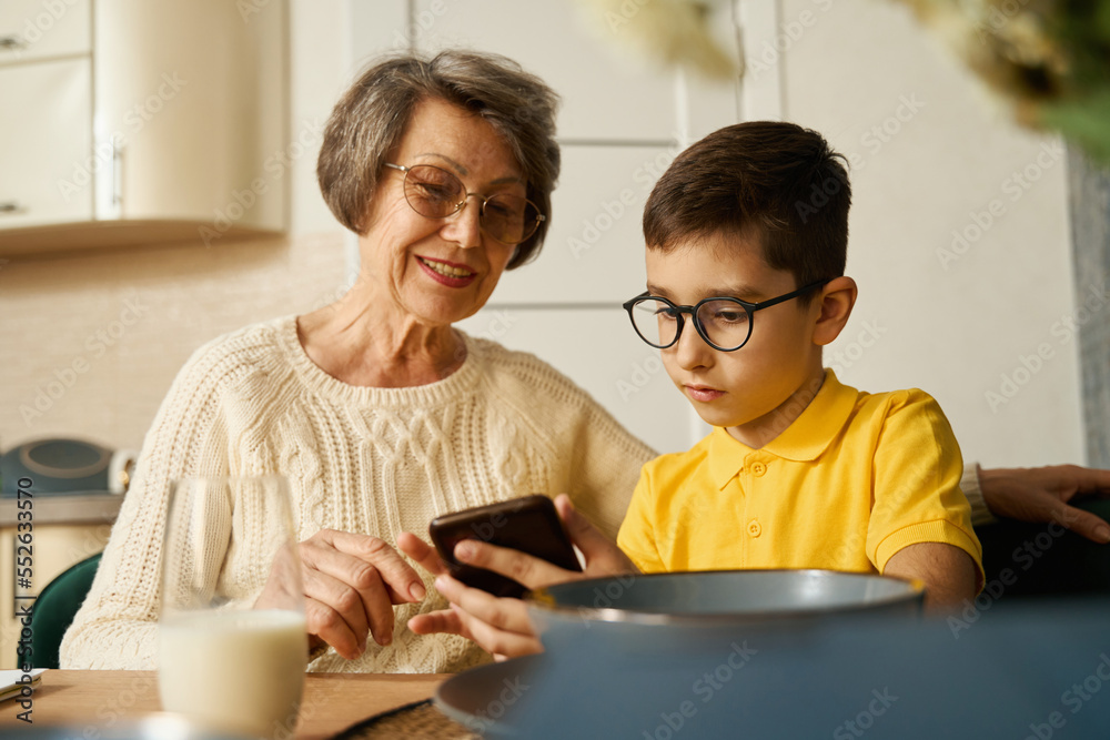Kid helping to grandmother find information in smartphone Kid helping to grandmother find information in smartphone