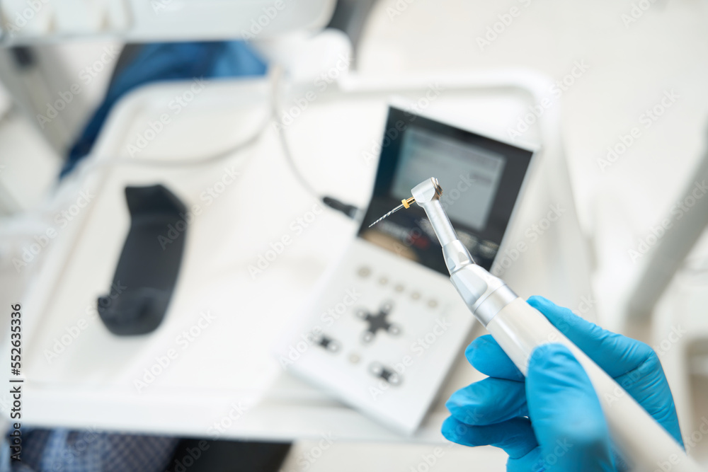 Dentist at his workplace in protective gloves holds thin drill Dentist at his workplace in protective gloves holds thin drill