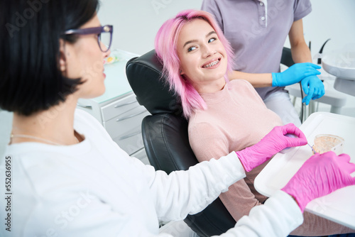 Smiling young woman sits comfortably in a dental chair