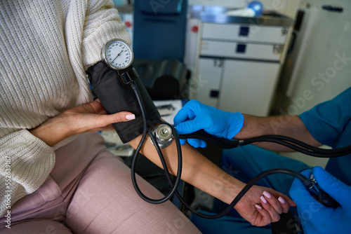 Woman sits with blood pressure monitor connected to her arm