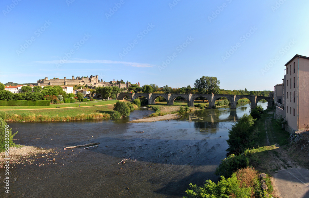 Aude river cityscape with old medieval stone bridge and the castle of Carcassonne, France