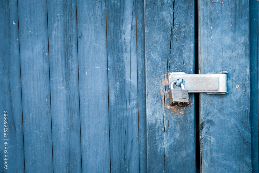 Old padlock and blue boards keep door locked. Old padlock and blue boards keep door locked.