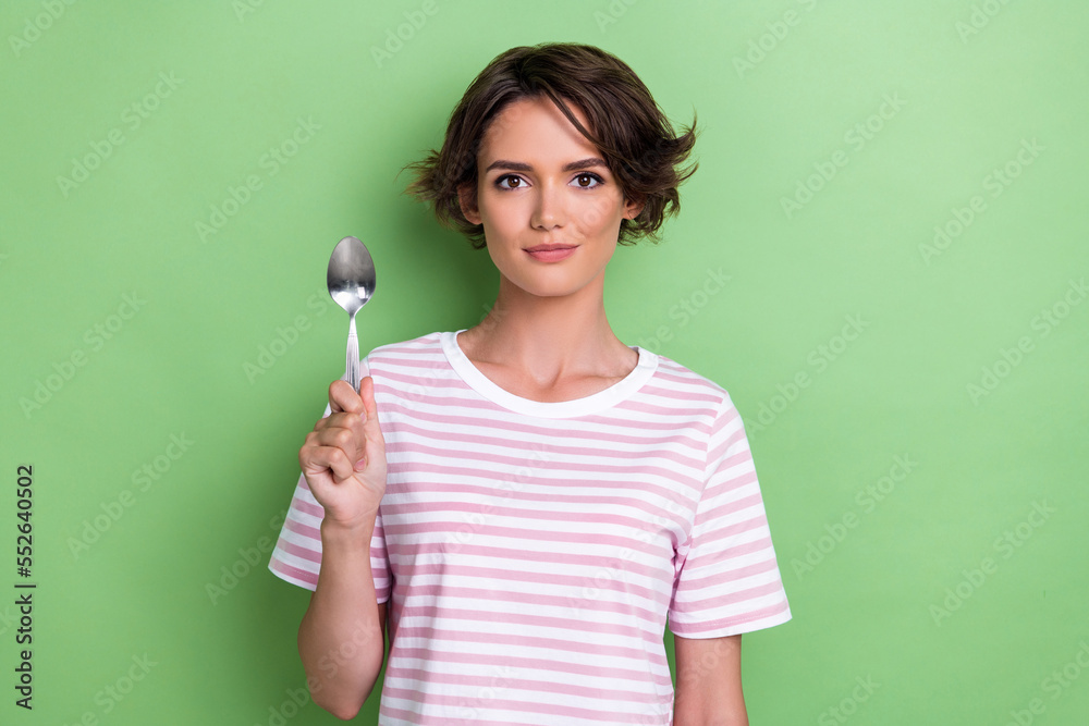 Photo of pretty calm lady trendy striped clothes hand arm hold metal silver spoon waiting meal starving isolated on green color background Photo of pretty calm lady trendy striped clothes hand arm hold metal silver spoon waiting meal starving isolated on green color background