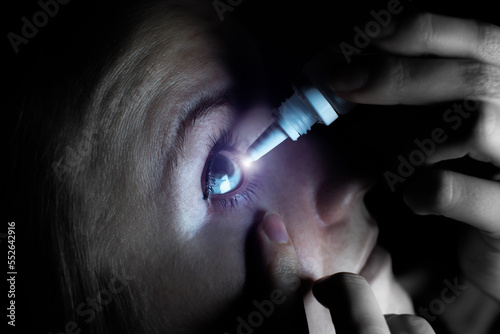 Woman is putting drops in his eyes. Medical treatment concept. Allergic conjunctivitis problem...Works on internet in front of computer all day. Eye pain, dry eye syndrome.