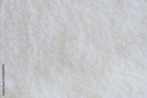 Light background with angora or wool. Soft beige knitted fabric as background, closeup. Fluffy fabric for the whole picture