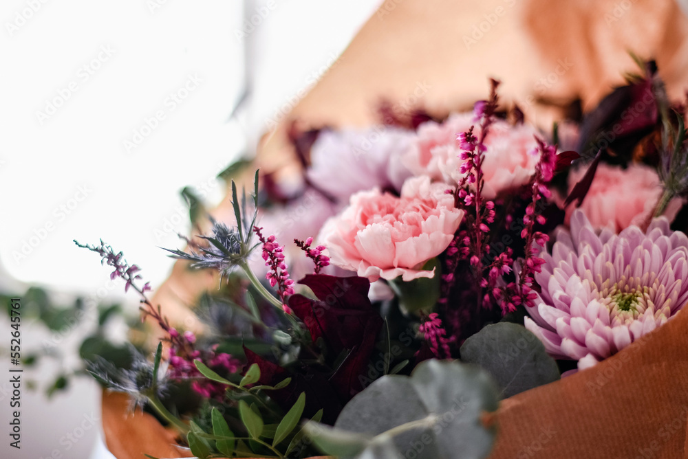 Detalle de las flores de un ramo en tonos rosas y granates. Eucalipto plateado, crisantemo, clavel, peonía y cardo azul.