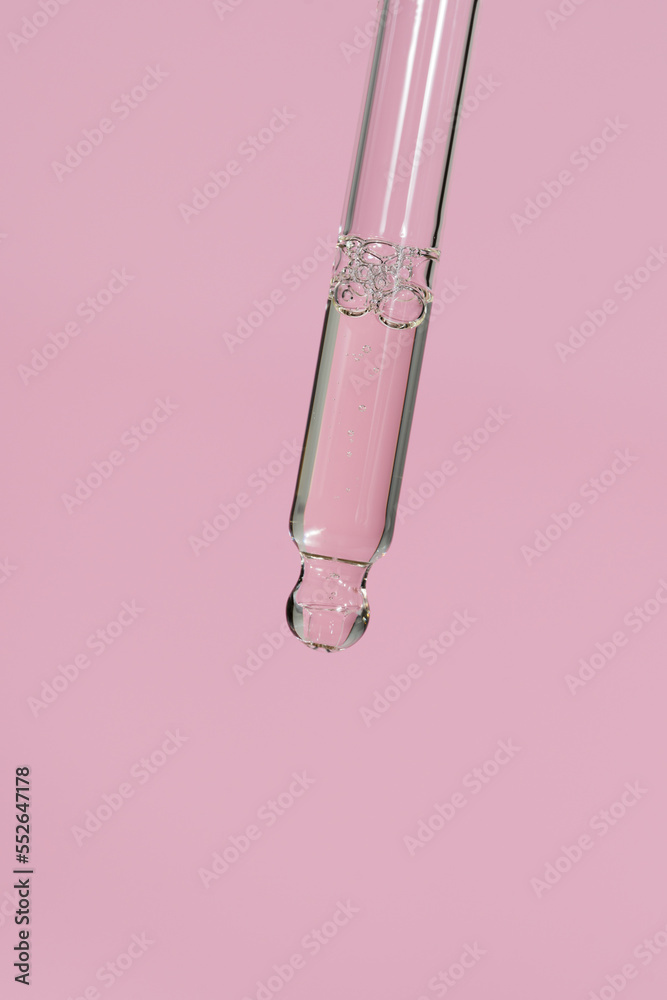 Transparent facial serum or oil in glass pipette on light pink background. Liquid gel with hyaluronic acid closeup. Trendy cosmetic product macro. Beauty routine. Copy space, front view. Transparent facial serum or oil in glass pipette on light pink background. Liquid gel with hyaluronic acid closeup. Trendy cosmetic product macro. Beauty routine. Copy space, front view.