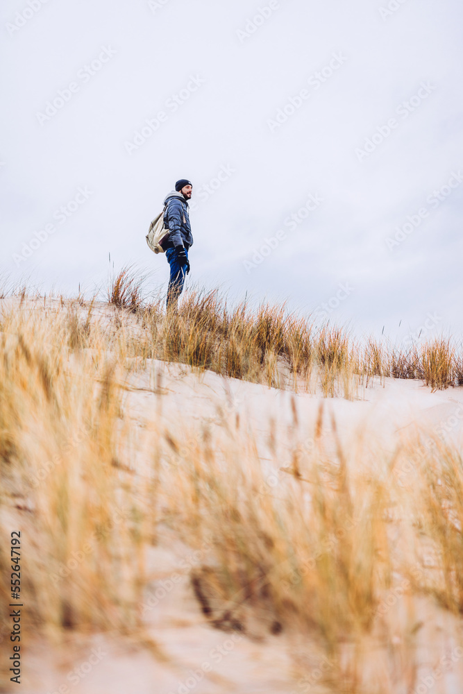Man trekking on dunes by the sea at autumn Man trekking on dunes by the sea at autumn