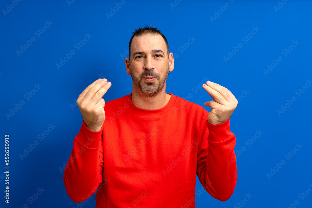Latin man about 40s with beard wearing red jumper over isolated blue background doing italian gesture with hands and fingers confident expression. Latin man about 40s with beard wearing red jumper over isolated blue background doing italian gesture with hands and fingers confident expression.