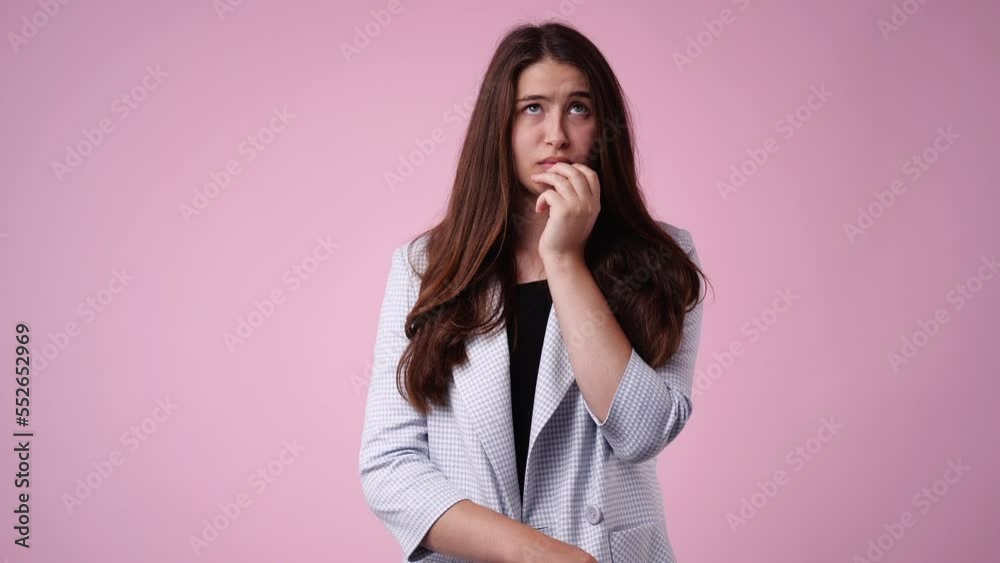 4k video of an upset girl who is nervous and bites her nails on pink background. 4k video of an upset girl who is nervous and bites her nails on pink background.