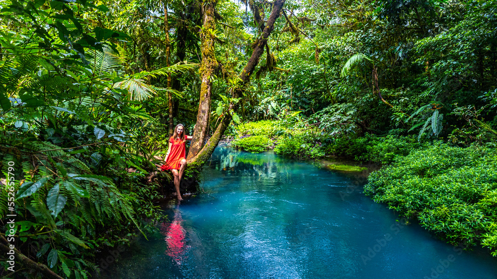 Girl In Red Dress Stands On The Banks Of The Famous Blue Rio Celeste girl-in-red-dress-stands-on-the-banks-of-the-famous-blue-rio-celeste