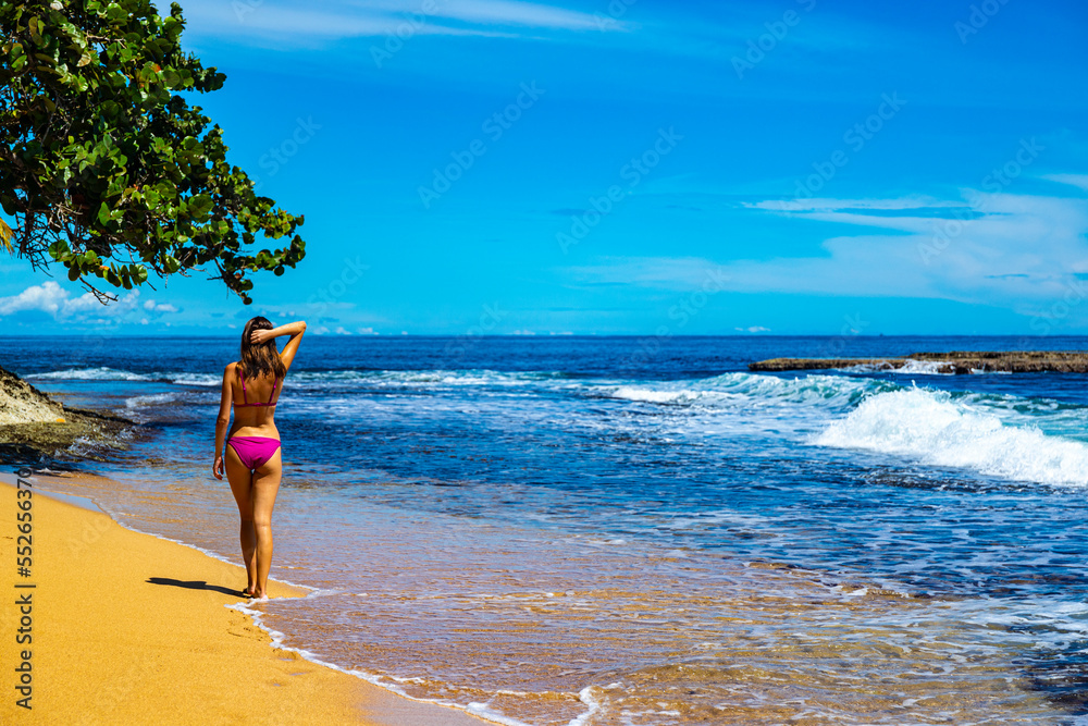 beautiful girl in a bikini walks on the sand on a Caribbean beach in Costa Rica; sunbathing on a paradise beach by the Caribbean sea, beach vacation in tropical Costa Rica