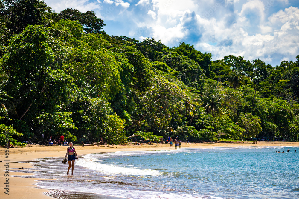 A backpacker girl walks along a paradise tropical beach on the Caribbean coast of Costa Rica; beach walk in Costa Rica