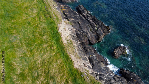 Dense thickets of grass on the shore. Grass-covered rocks on the Atlantic Ocean coast. Nature of Ireland, top view. Aerial photo.