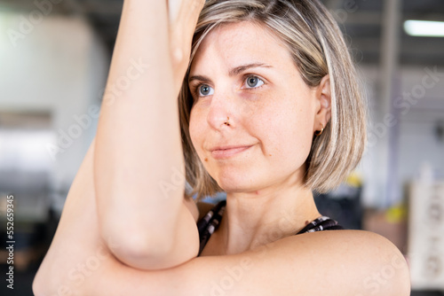 Close-up photo of a happy mid adult woman in an eagle pose or garudasana during her vinyasa flow yoga practice indoors