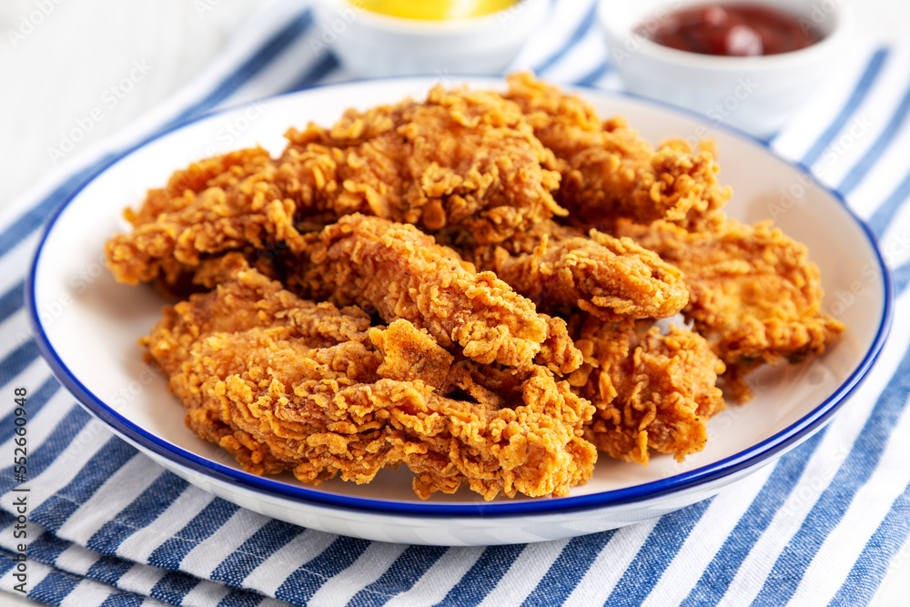 Homemade Chicken Strips with Mustard and BBQ on a Plate, side view. Close-up. Homemade Chicken Strips with Mustard and BBQ on a Plate, side view. Close-up.