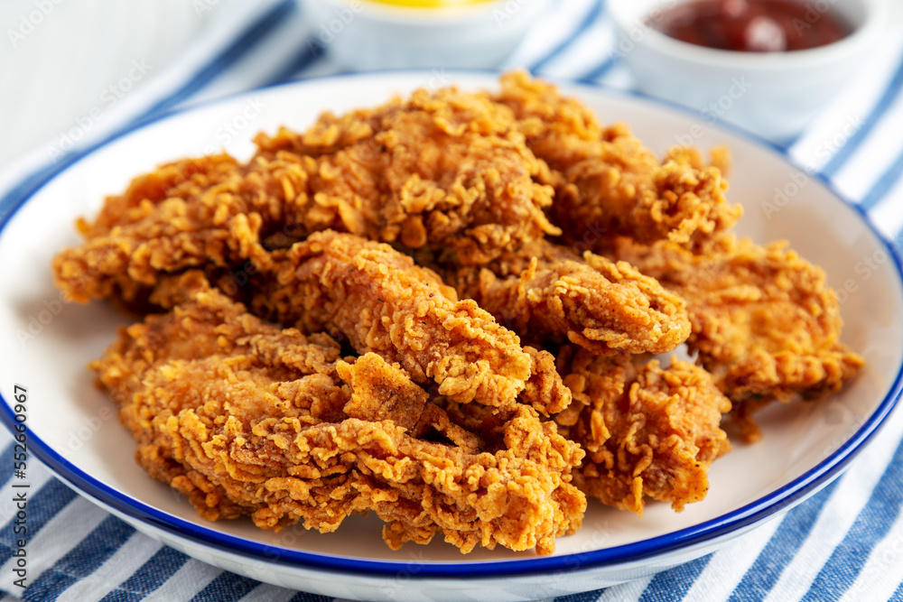 Homemade Chicken Strips with Mustard and BBQ on a Plate, side view. Close-up. Homemade Chicken Strips with Mustard and BBQ on a Plate, side view. Close-up.