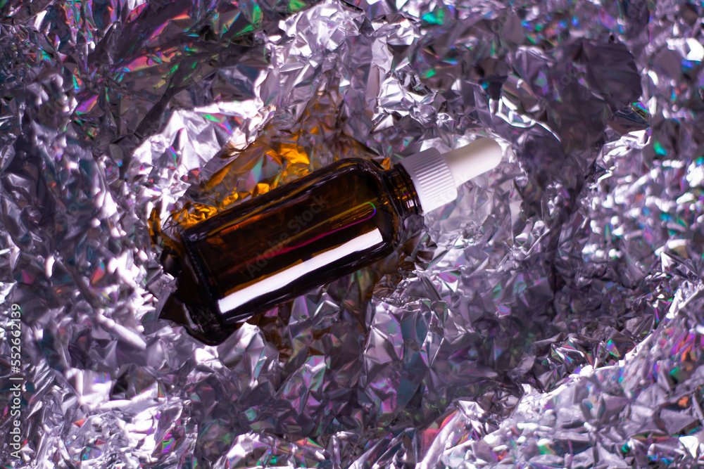 Glass bottle with natural body oil cosmetics on hologram background.