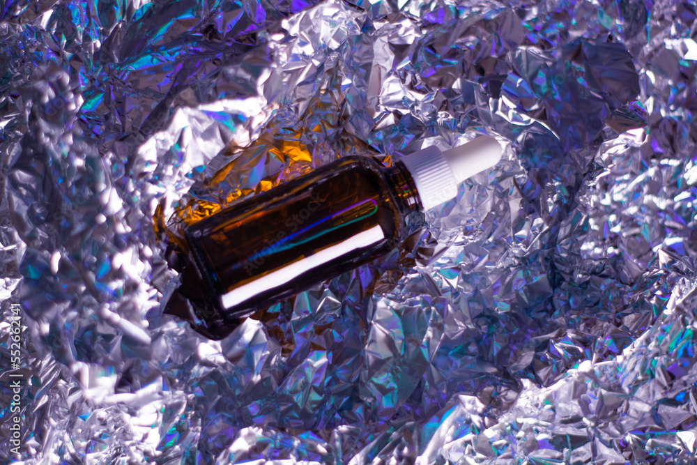Glass bottle with natural body oil cosmetics on hologram background.