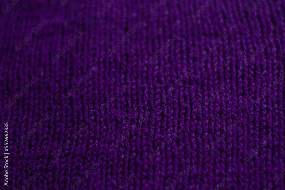 Knitted sweater with small braid, plain purple background.