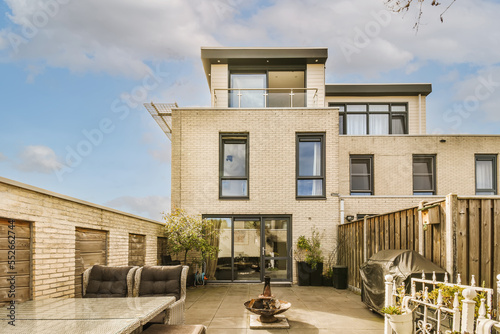 an outdoor living area with couchs, tables and chairs in front of a brick building on a sunny day photo