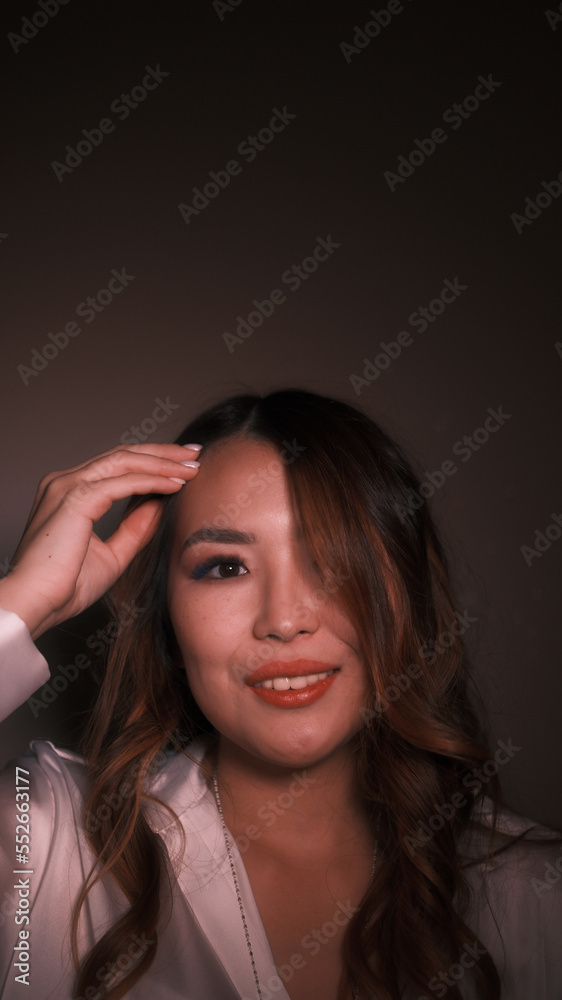 Obraz premium Girl straightens her hair and looks at the camera