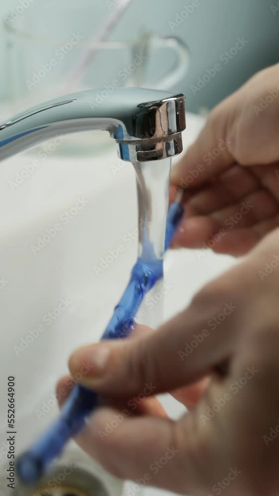 female hands wash a reusable straw made of blue glass under a stream of warm water with a special hard brush. The concept of saving ecology by abandoning disposable tableware and items. Zero Waste female hands wash a reusable straw made of blue glass under a stream of warm water with a special hard brush. The concept of saving ecology by abandoning disposable tableware and items. Zero Waste