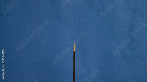 a stick of incense against the blue photo