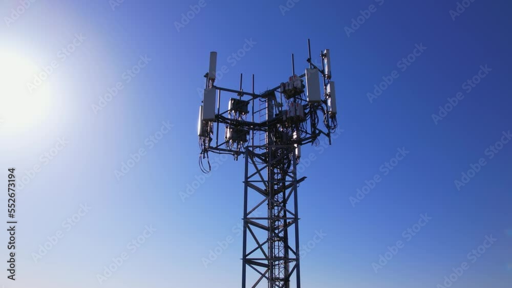 Aerial view of tower antennas with telecommunication, cell phone and radio transmitters. Around view at golden hour evening with sun leaks. Cellular signals for 5g, 4g mobile data and smart phones.