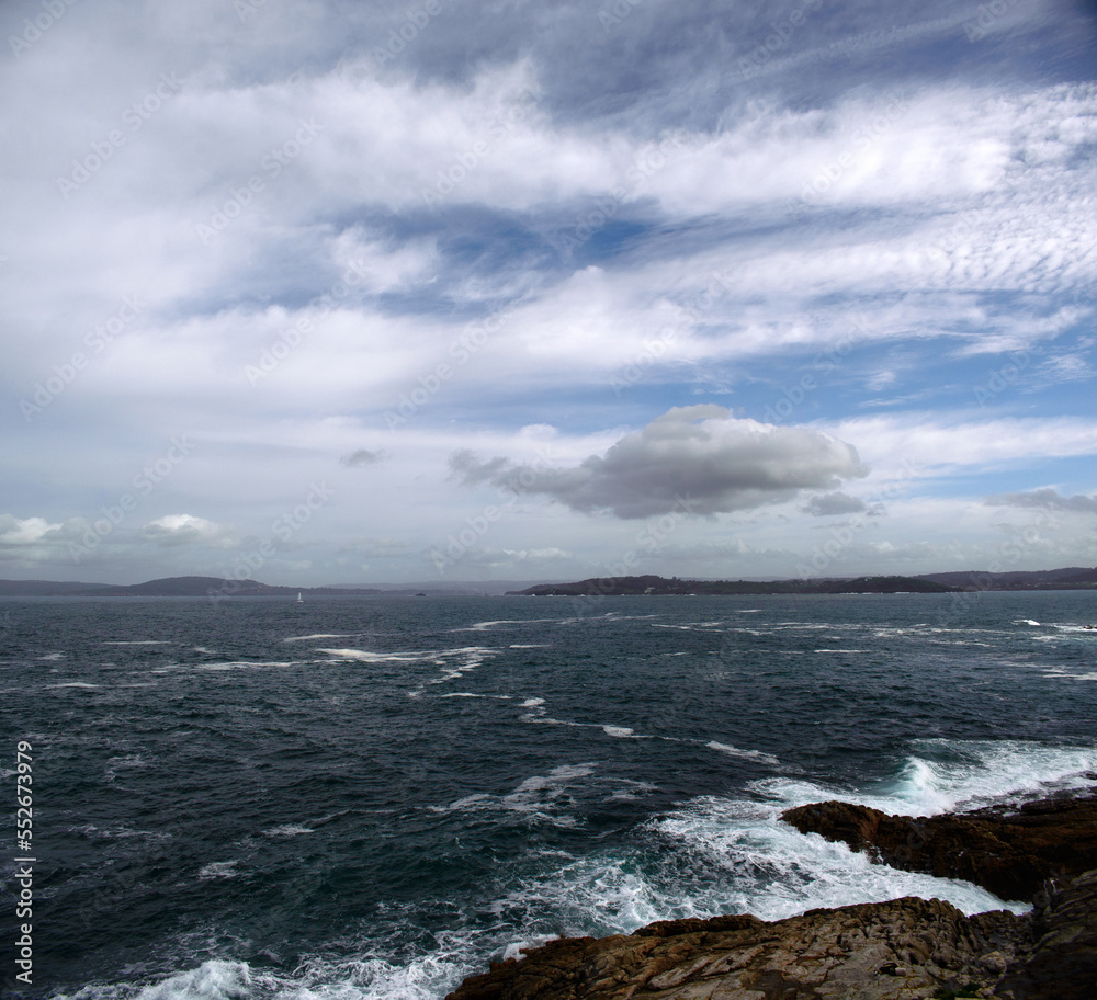 Stormy sea beats against the rocks against the background of a sky with clouds