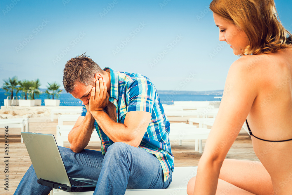 Couple with laptop on the beach