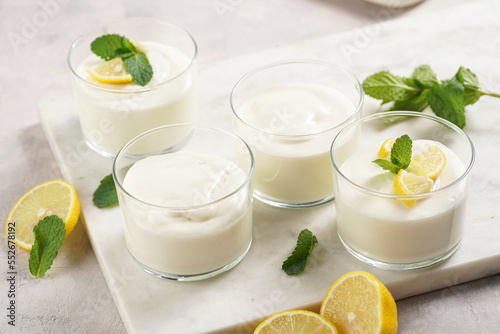 Creamy dairy yoghurt dessert sweet mousse with mascarpone, cream cheese, mint and lemon juice in glasses on marble tray