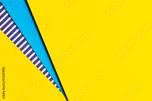 Abstract geometric bright colored papers texture background. Yellow background and blue, striped paper with blue and white stripes between. Top view, flat lay photo