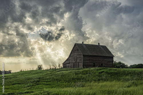 Abandoned barn with storm clouds converging overhead; Nebraska, United States of America