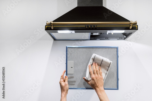 woman washing cooker hood filter at kitchen