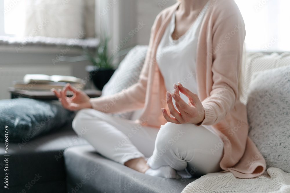 Young woman sitting in meditation pose at home