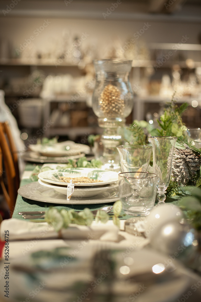 Festive christmas table setting with white and green color plates, tableware, glasses and candles and holiday season decor.	
