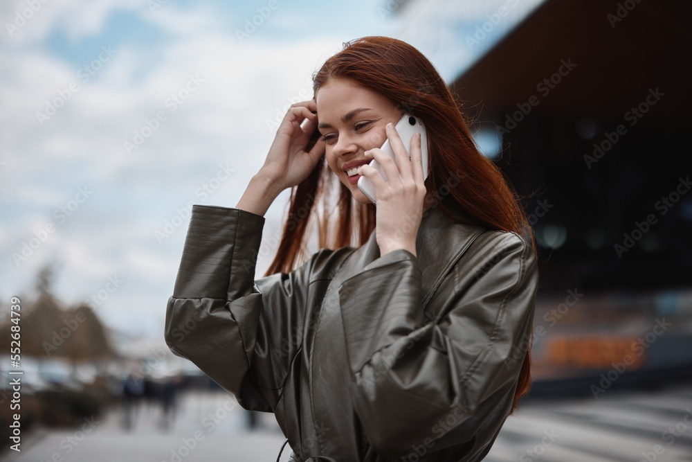 Woman business talking on the phone and smiling in front of city buildings, the concept of technology and business development online Woman business talking on the phone and smiling in front of city buildings, the concept of technology and business development online