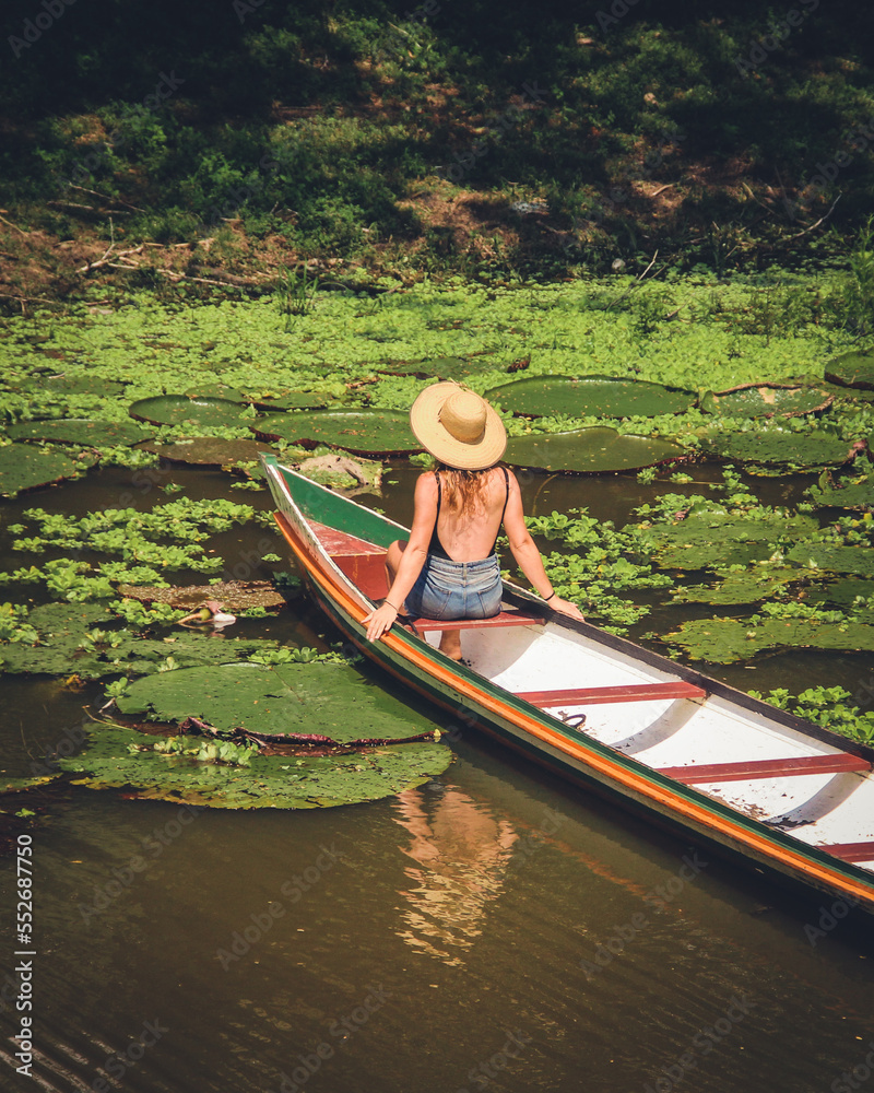 Mulher não identificada, de costas, com chapéu, em barco no rio croa, cercado de vitórias-régias, em cruzeiro do sul, Acre 