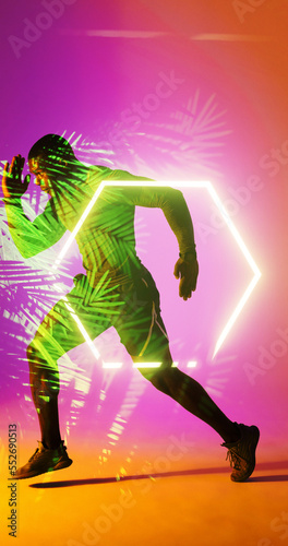 Fototapeta Naklejka Na Ścianę i Meble -  Side view of african american rugby player running by illuminated hexagon and plants, copy space