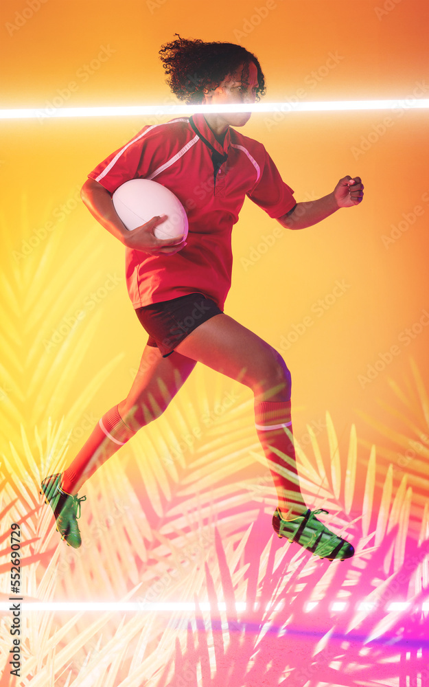 Biracial female rugby player holding ball and jumping over illuminated line and plants
