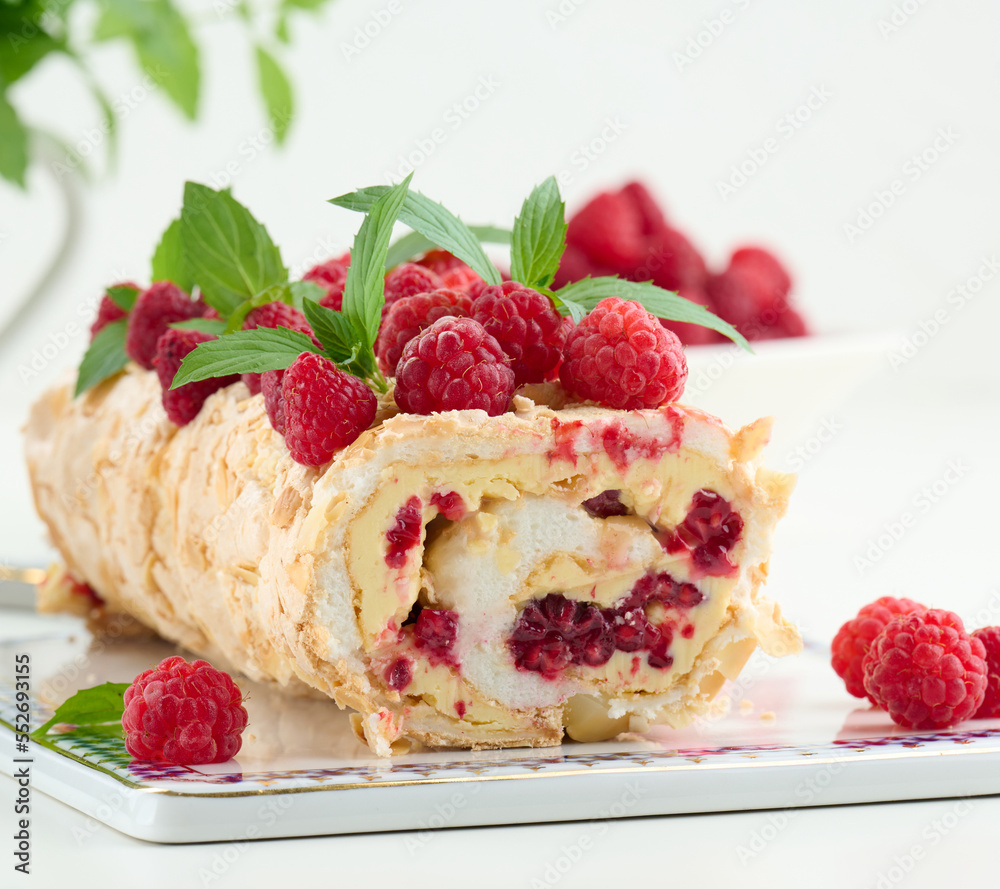Baked meringue roll with cream and fresh red raspberry, white background Baked meringue roll with cream and fresh red raspberry, white background