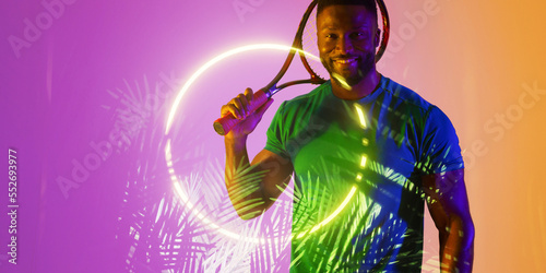 Illuminated plants and circle over smiling african american male player holding tennis racket