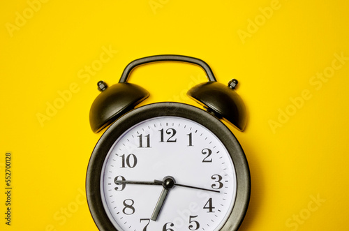 black vintage alarm clock on yellow colour background