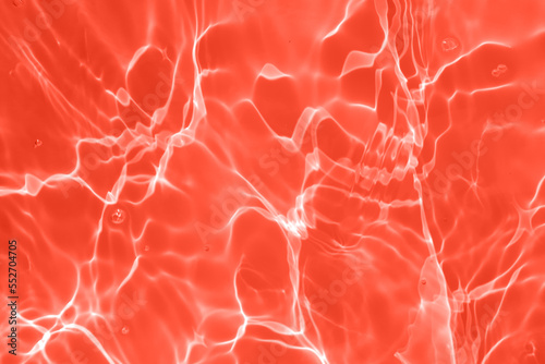 Defocus blurred transparent red colored clear calm water surface texture with splashes and bubbles. Trendy abstract nature background. Water waves in sunlight with copy space. Red watercolor shining