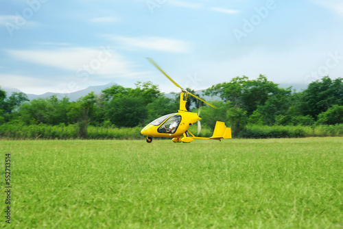 Fotografia Yellow rotorcraft flying above grass near trees